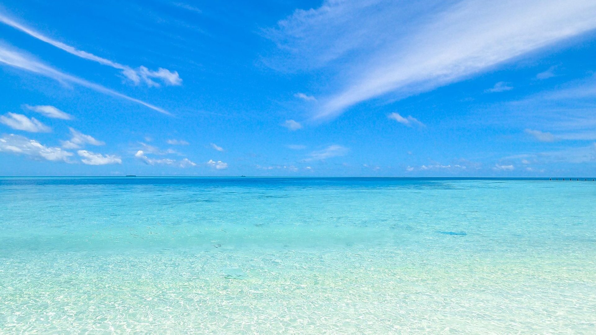 Experience the tranquil turquoise waters and clear sky at Laamu Atoll, Maldives. Perfect for a relaxing getaway.